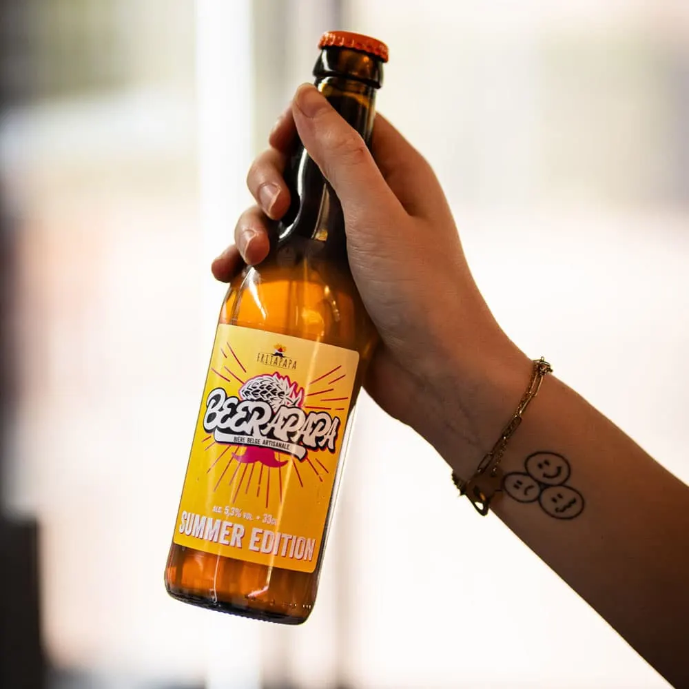 Bouteille Beerapapa Summer Edition tenue en main devant une friterie